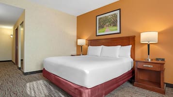 A hotel room with a large bed, two bedside tables with lamps, a wooden headboard, and a framed picture on the wall.