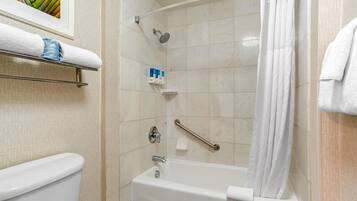 A bathroom with a white bathtub, a shower with a handheld showerhead, a grab bar, and a towel rack with a folded towel.