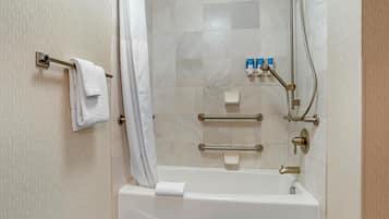 Une salle de bain équipée d’une baignoire, d’un porte-serviettes, d’un pommeau de douche et d’une barre d’appui.