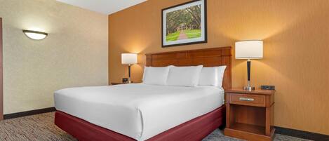 A hotel room with a large bed, two bedside lamps, a nightstand, and a framed picture on the wall.