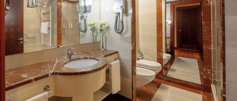 A modern bathroom with a marble sink, a large mirror, a towel rack, and a toilet.