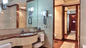 A modern bathroom with a large mirror, dual sinks, a vanity, and a shower.