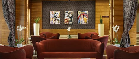 Eine Lobby mit einem roten Sofa, einem Couchtisch mit Büchern und drei Bildern an der Wand.
