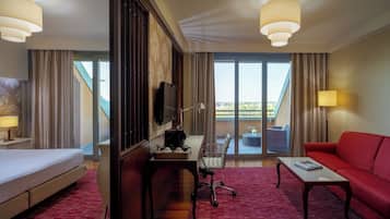 A hotel room with a bed, a desk, a red sofa, and a TV.