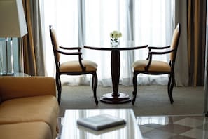 Ein Hotelzimmer mit einem runden Tisch, zwei Stühlen, einem Sofa und einer Vase mit Blumen.
