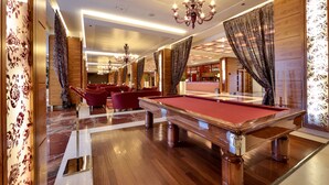 A billiards table in a well-lit room with red cushions, wooden paneling, and a chandelier. - UNA Hotels Expo Fiera Milano (Pero)