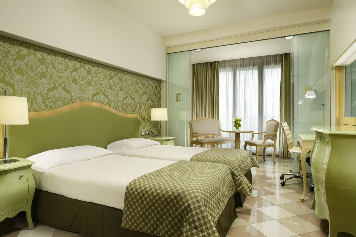 Une chambre d’hôtel avec deux lits, un bureau, une chaise et une petite table.