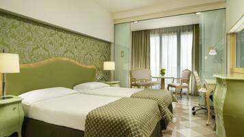 A hotel room with two beds, a desk, a chair, and a small table.