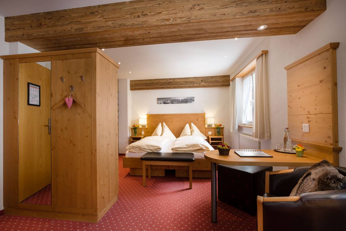 A wooden bedroom with a bed, a desk, and a wardrobe.
