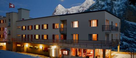 A hotel with multiple balconies and a view of snow-covered mountains.