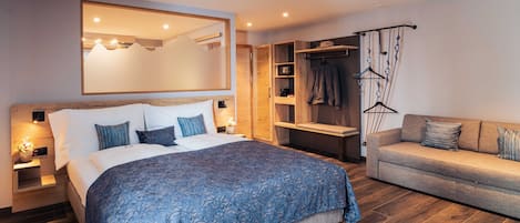 Un dormitorio moderno con una cama grande, un sofá, un armario y un espejo.