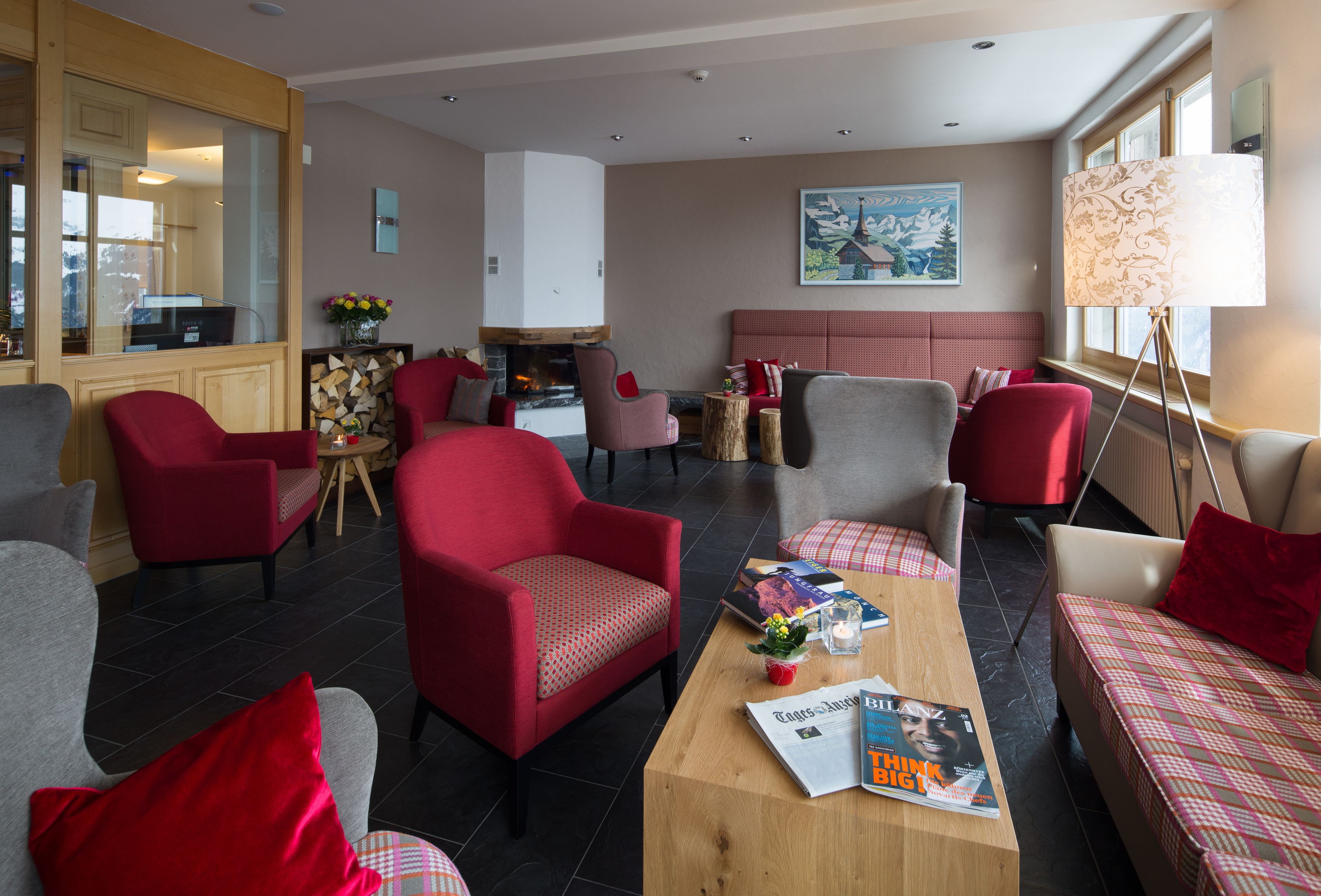 Una sala de estar moderna con muebles rojos y grises, una chimenea y un ventanal grande.