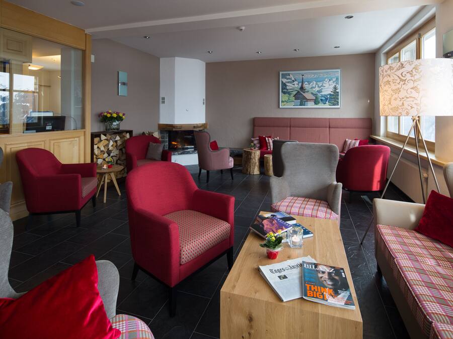 Una sala de estar moderna con muebles rojos y grises, una chimenea y un ventanal grande.
