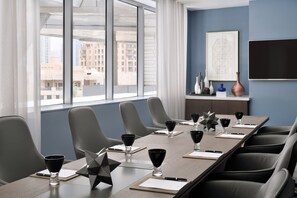 A conference room with a long table, multiple chairs, and black glasses on the table.