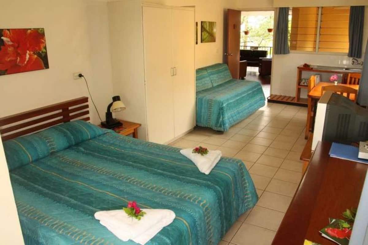 A hotel room with two beds, a desk, a chair, and a small kitchenette.