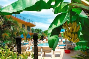 A poolside area with lounge chairs and a building in the background. - Nadi Bay Resort Hotel (Nadi)