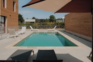 A rectangular swimming pool with two lounge chairs and a large umbrella. - greet hôtel Le Teich Bassin d'Arcachon (Le Teich)