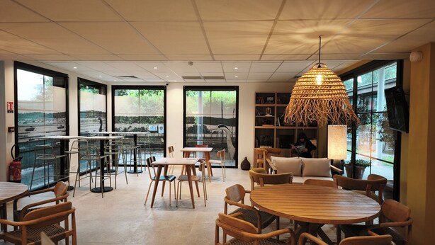 Un interior moderno con ventanas amplias, mobiliario de madera y una lámpara colgante original.