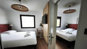 Una habitación de hotel con dos camas, un escritorio, un televisor y una ventana.