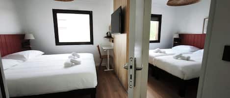 Ett hotellrum med två sängar, ett skrivbord, en TV och ett fönster.