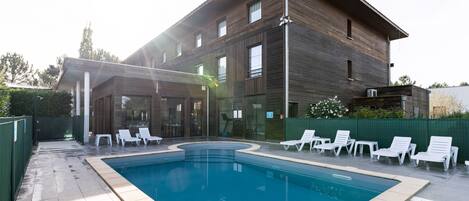 Een buitenzwembad, ligstoelen bij het zwembad