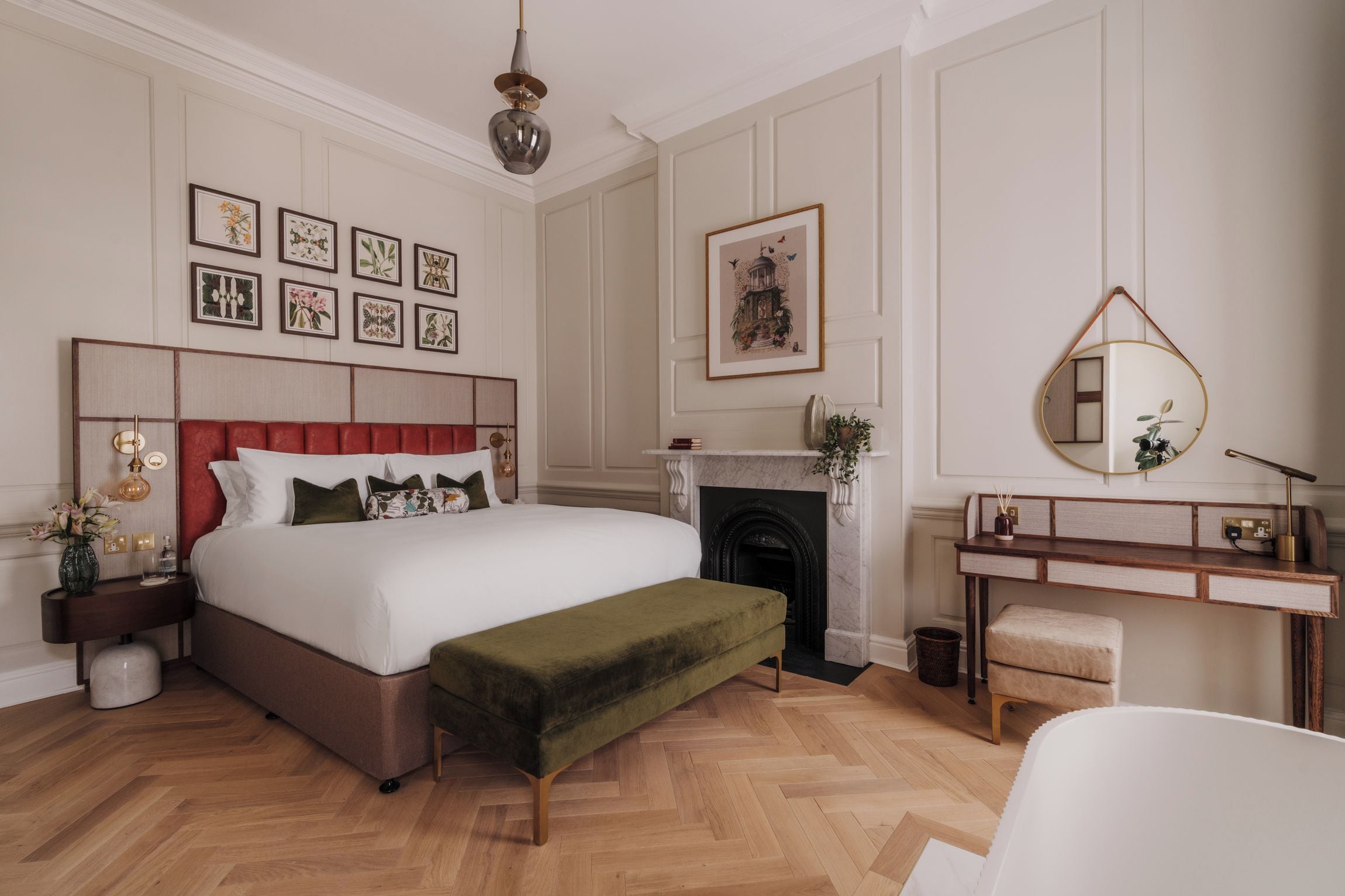 Een stijlvol ingerichte slaapkamer met een groot bed, nachtkastje, kaptafel, spiegel en een open haard.