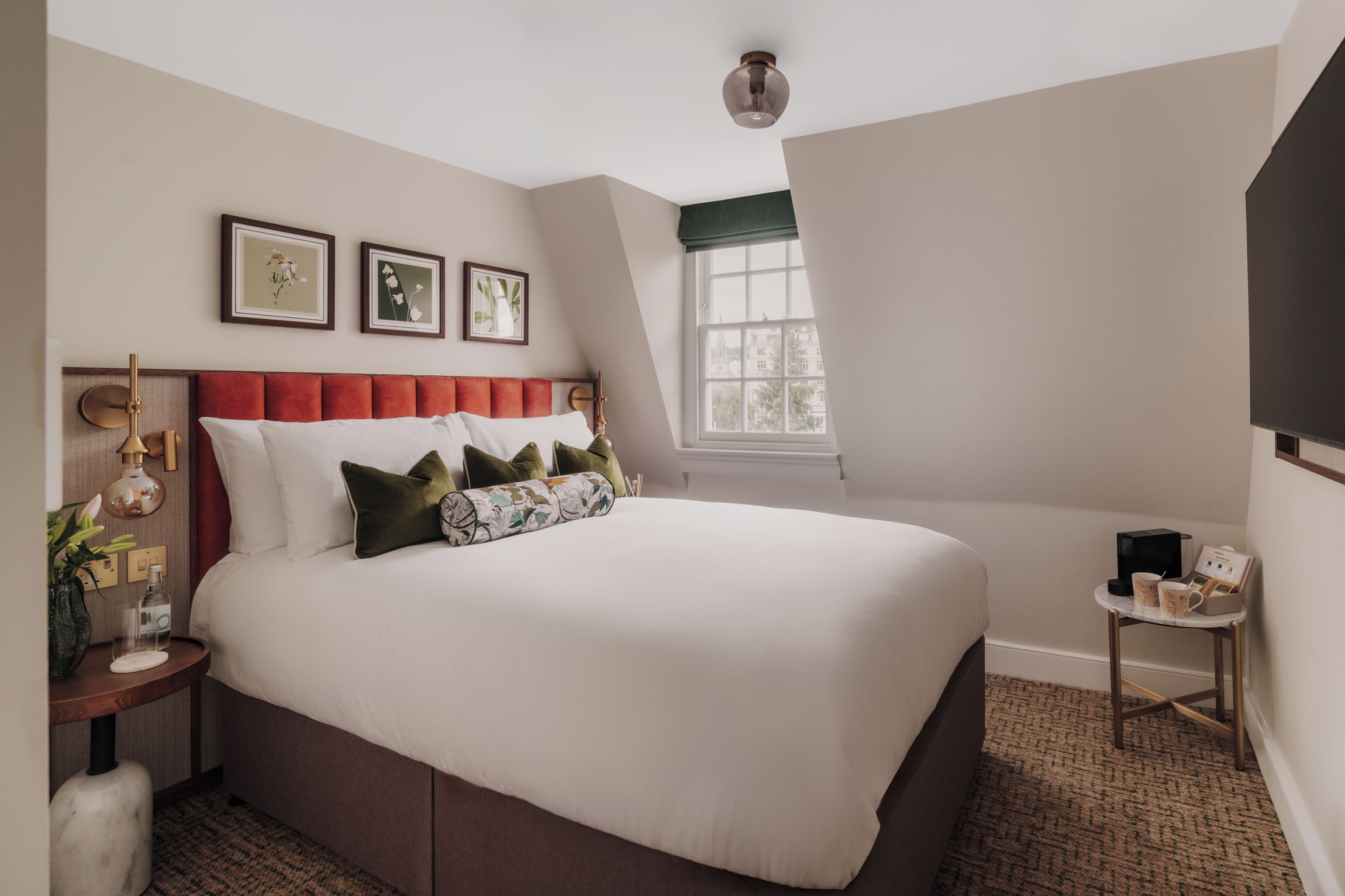 Une chambre à coucher bien aménagée, avec un grand lit, une table de chevet, une commode et une fenêtre donnant sur un beau paysage.