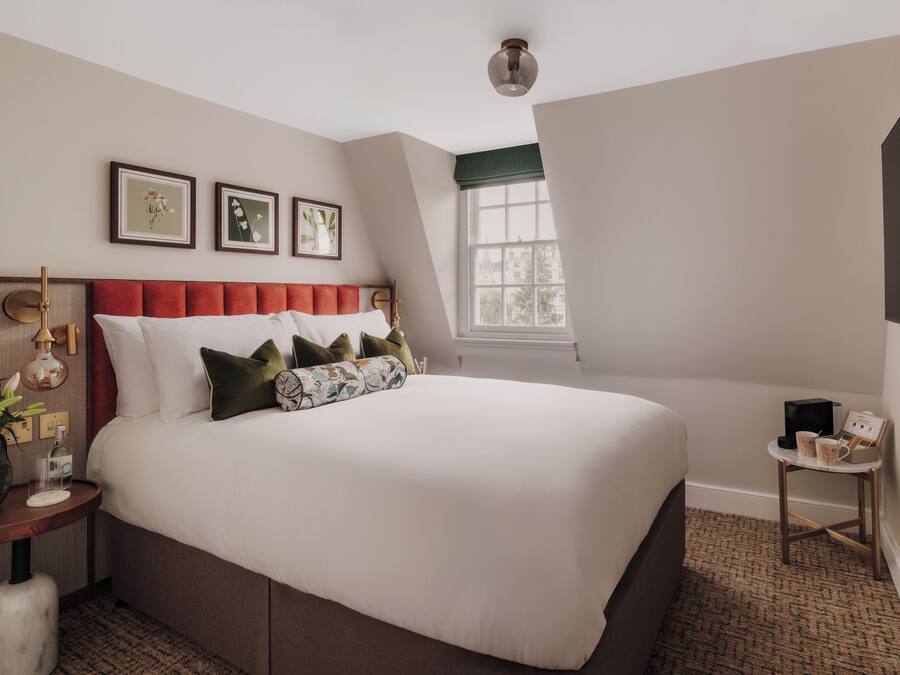 Une chambre à coucher bien aménagée, avec un grand lit, une table de chevet, une commode et une fenêtre donnant sur un beau paysage.