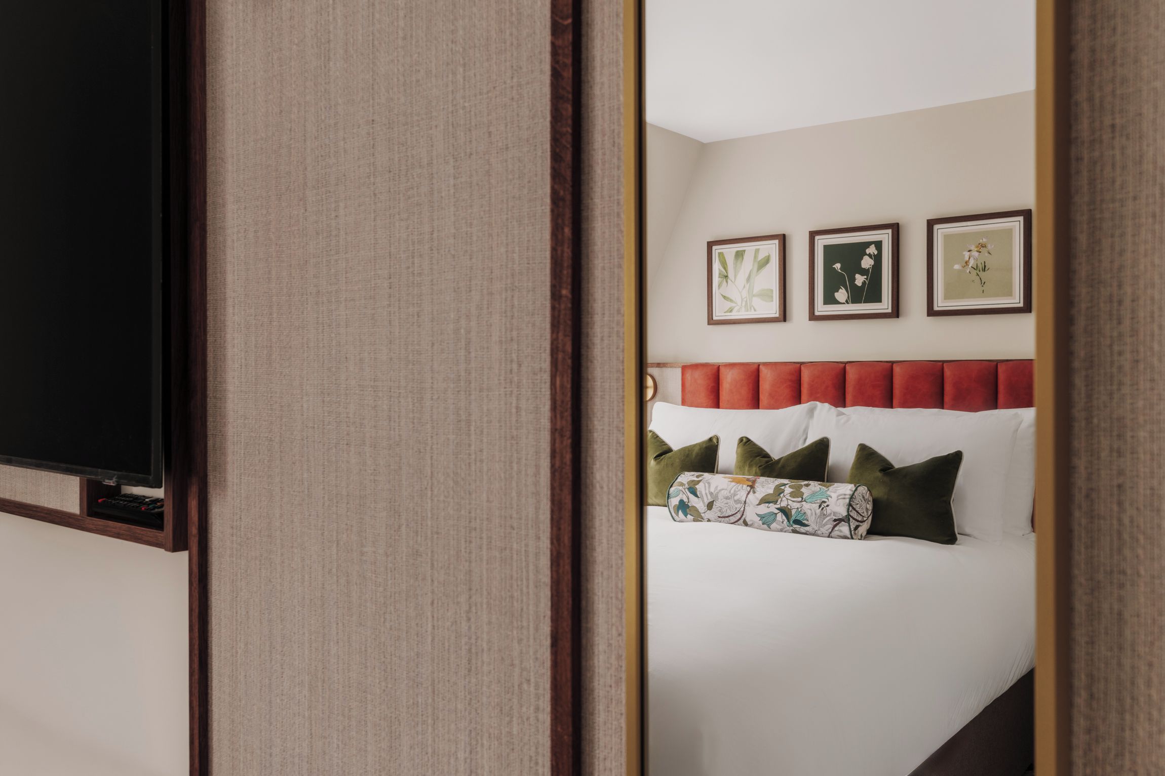 Una camera d'albergo con un letto, una televisione e tre quadri appesi al muro.