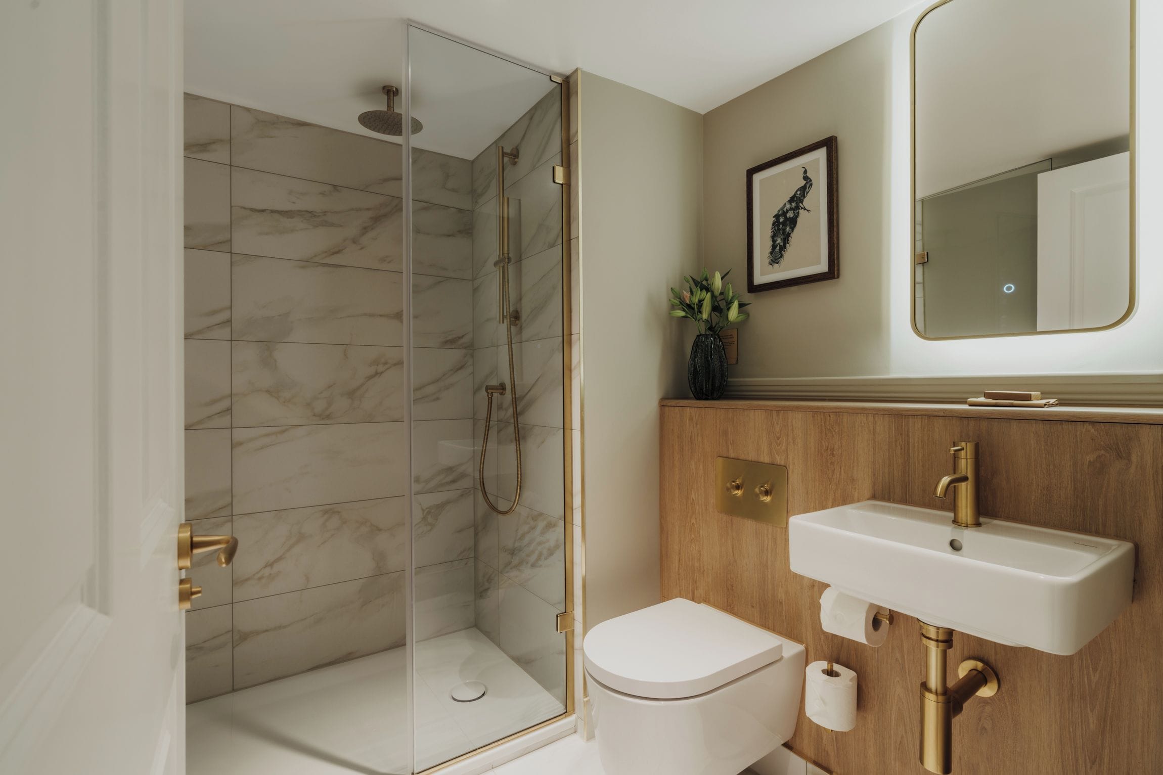 Un baño moderno con ducha acristalada, tocador de madera y inodoro blanco.