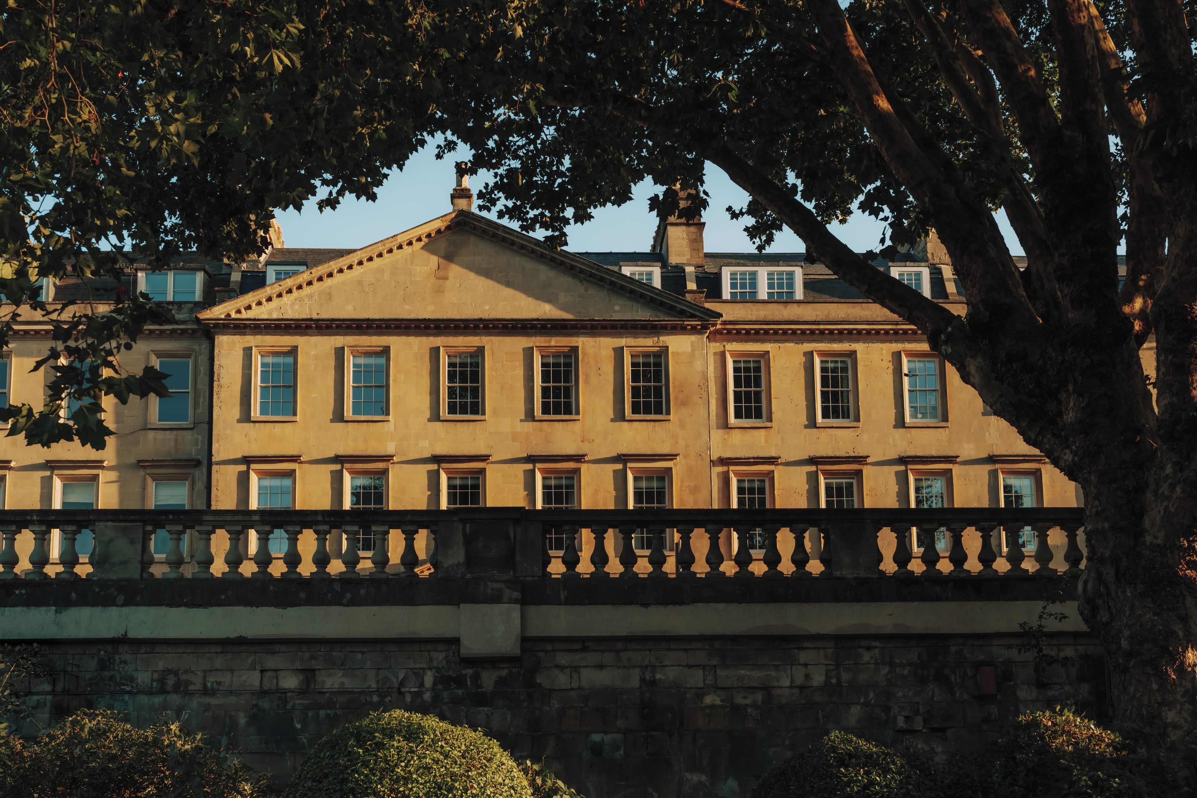 A historic building with a symmetrical facade, multiple windows, and a balcony with balustrades.