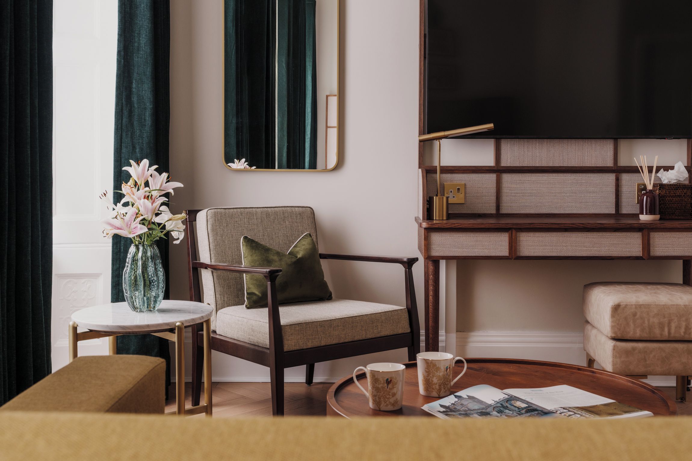 Una sala de estar moderna con sofá, sillón, mesa de centro y mueble de TV con televisor de pantalla plana.