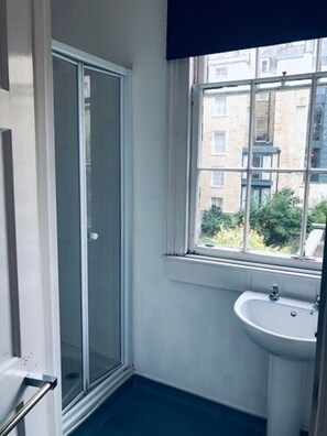 A bathroom with a window, a sink, and a shower. - Parade Hotel Bath (Bath)