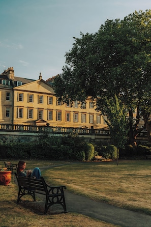 A park with a bench and a building in the background. - Parade Hotel Bath (Bath)