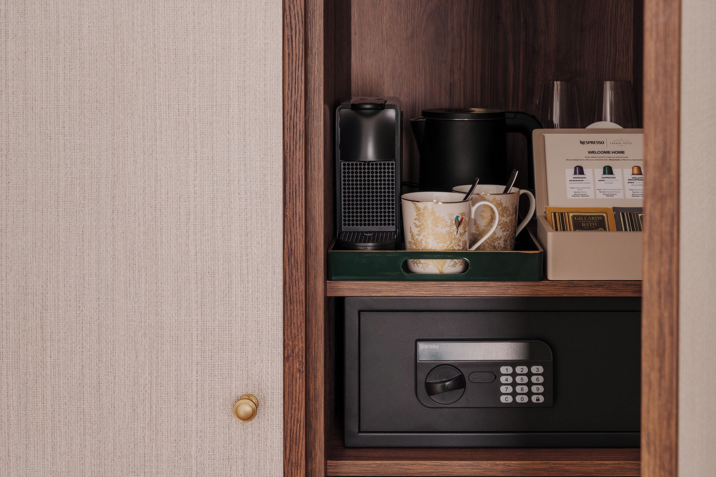 Un mini refrigerador con una cafetera, una taza y una caja de cápsulas de café.