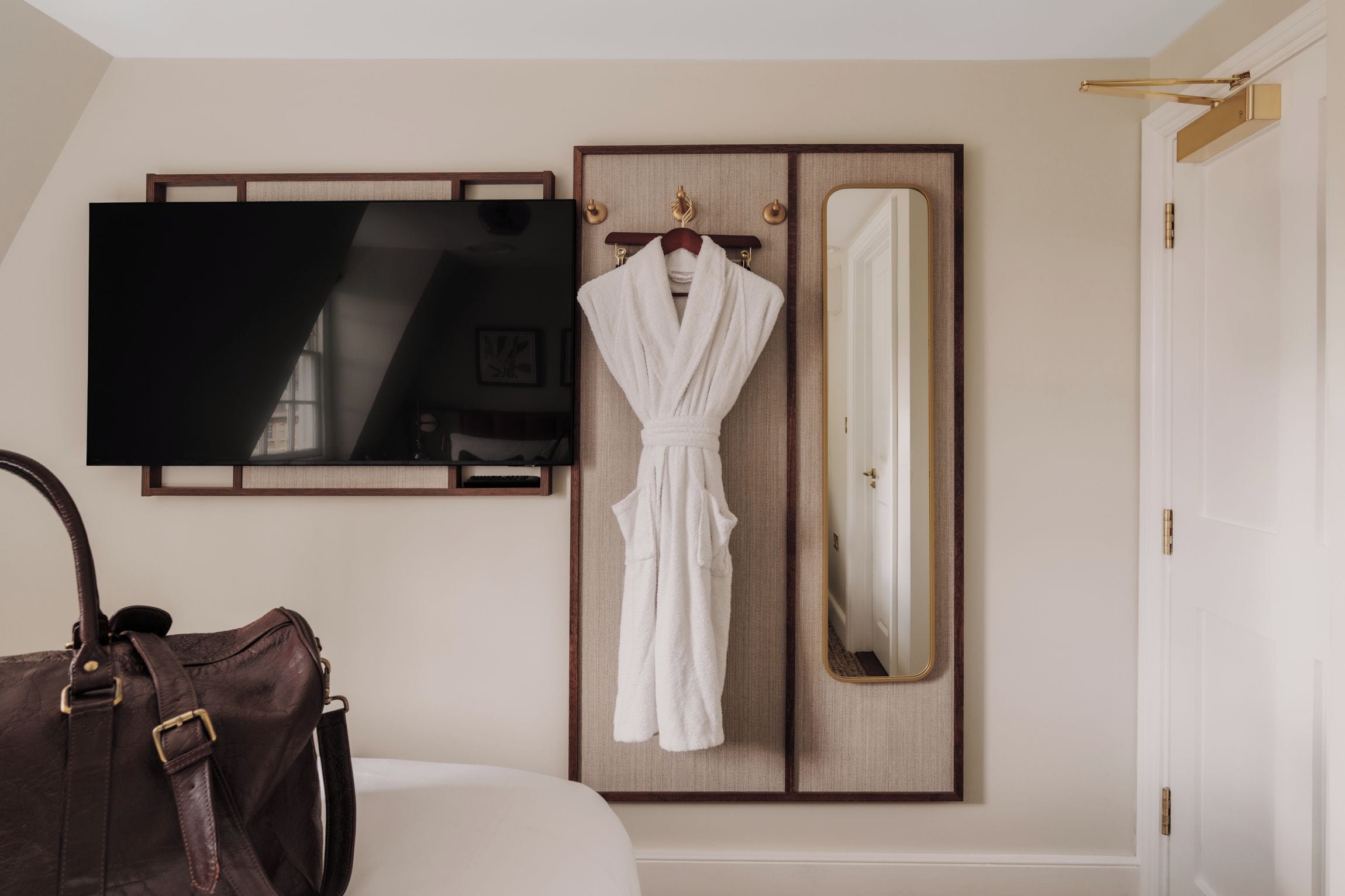 Ein Hotelzimmer mit Bett, Fernseher, Bademantel und Spiegel.