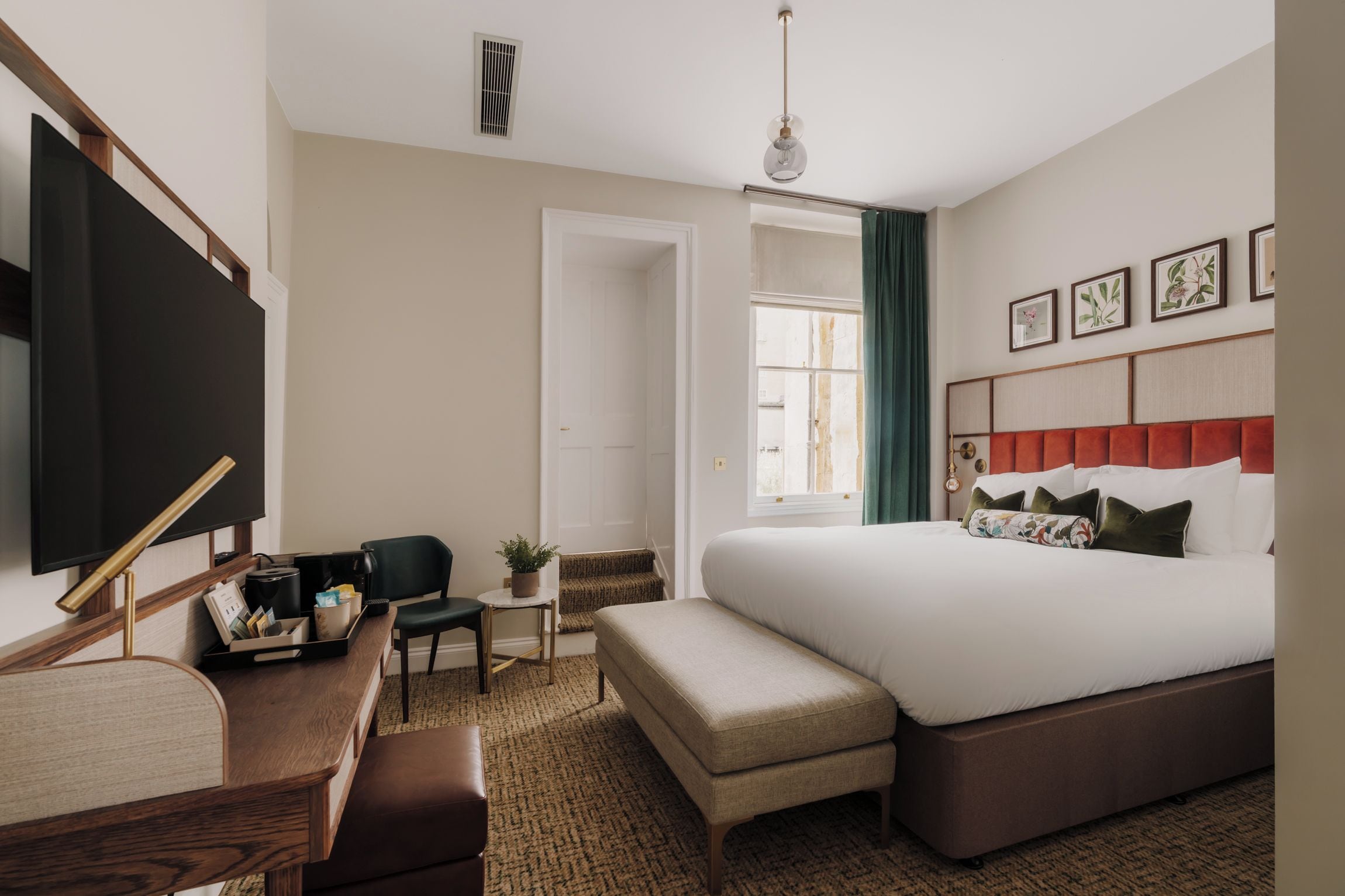 A hotel room with a bed, a desk, a chair, a television, and a window with curtains.