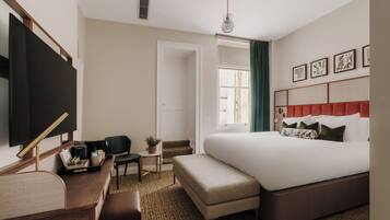 A hotel room with a bed, a desk, a chair, a television, and a window with curtains.