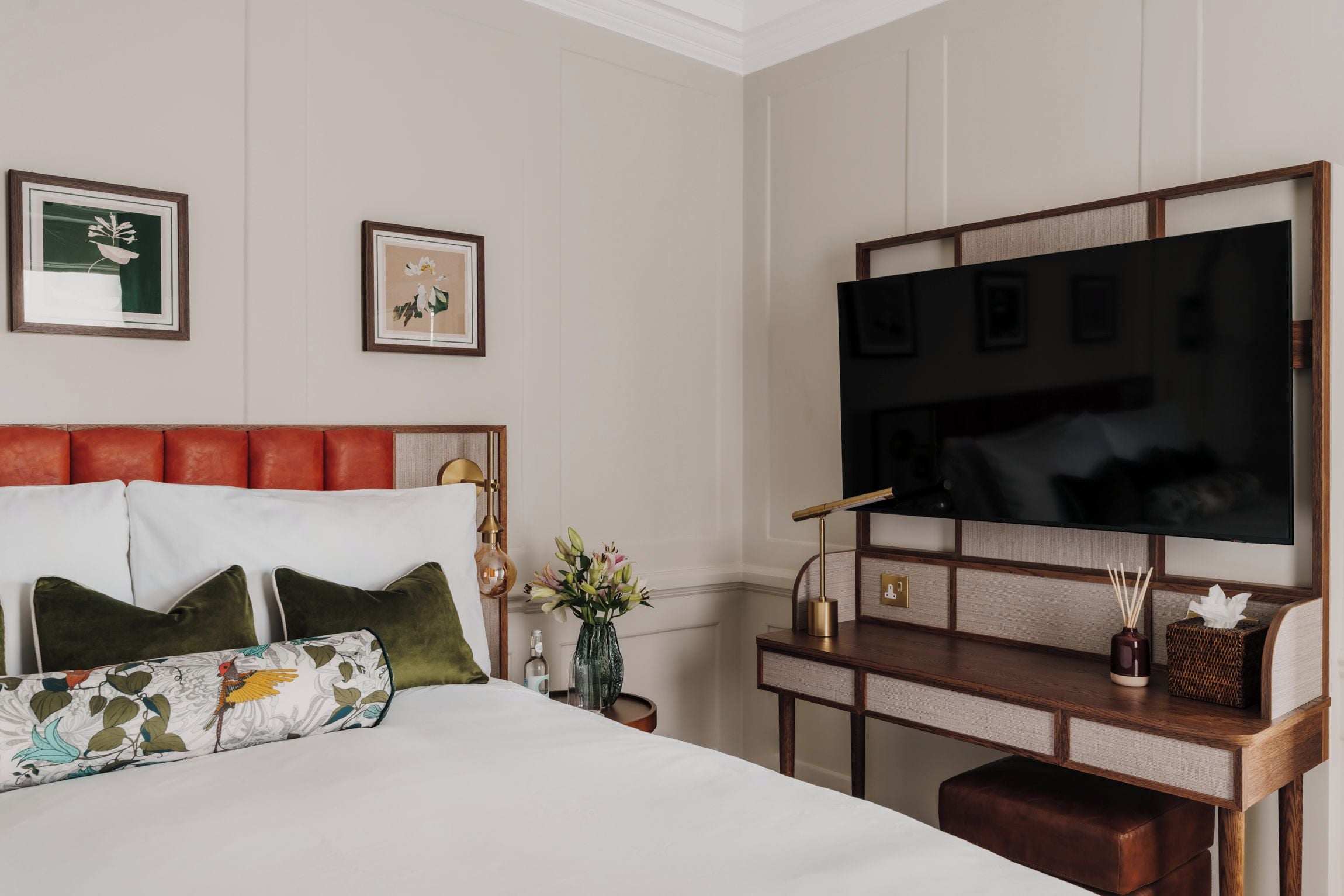 A hotel room with a bed, a TV, and a desk with a lamp.