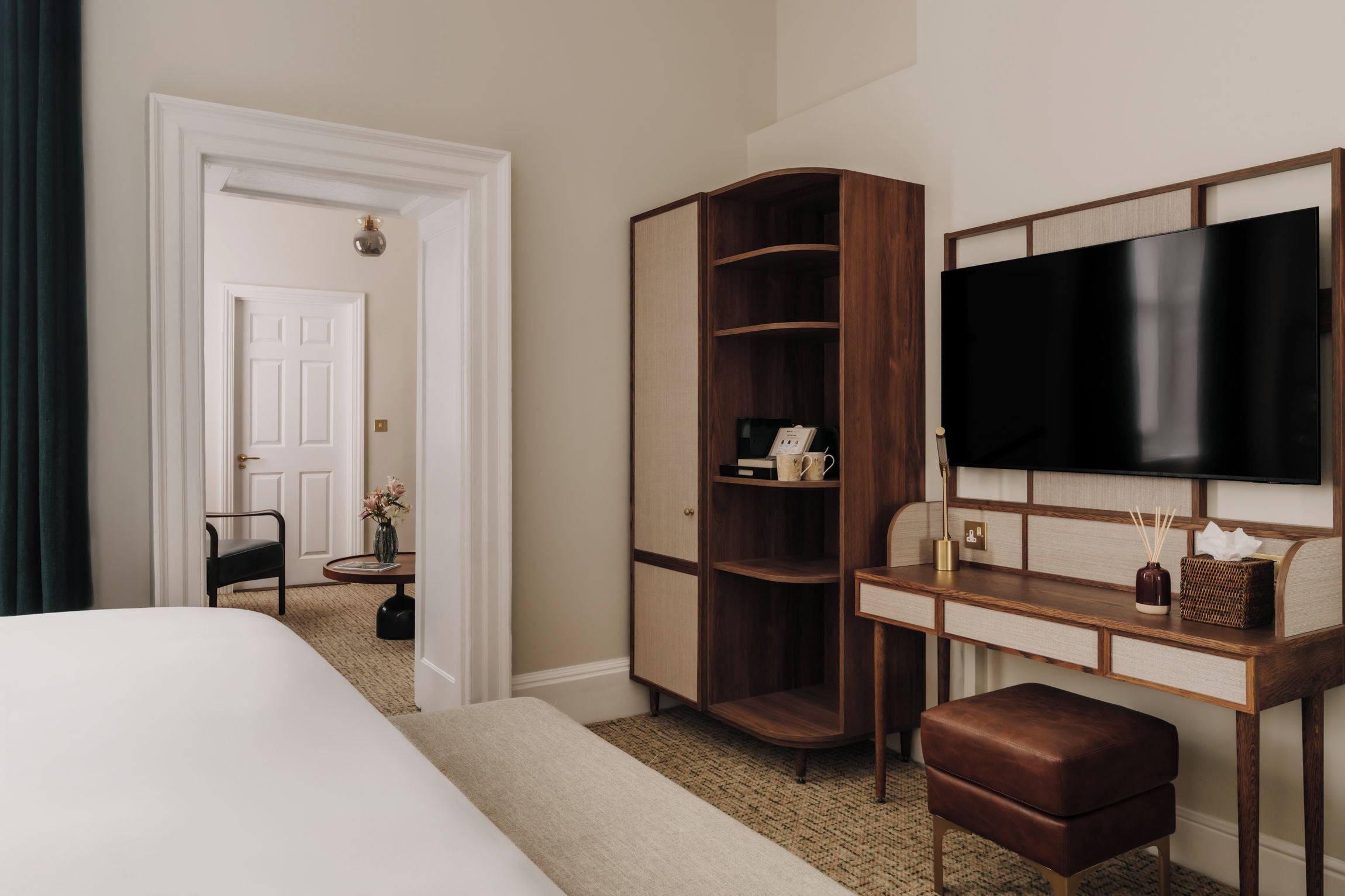Une chambre d’hôtel comprenant un lit, un bureau avec un téléviseur à écran plat, une armoire en bois et une chaise.