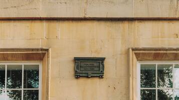 Une façade d’immeuble ornée d’une plaque indiquant le nom et les dates.