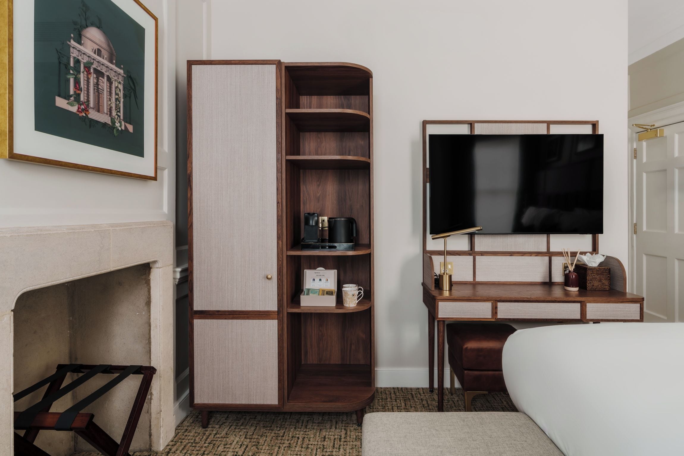 Ein Hotelzimmer mit Einbauschrank, Schreibtisch und Flachbildfernseher sowie einem Bett.