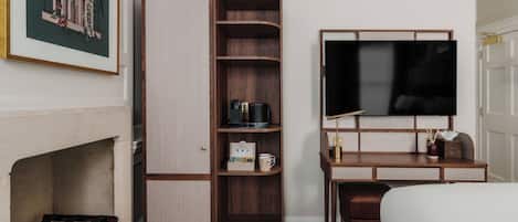 Ein Hotelzimmer mit Einbauschrank, Schreibtisch und Flachbildfernseher sowie einem Bett.