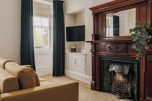 A living room with a sofa, a fireplace, a television, and a window with curtains.