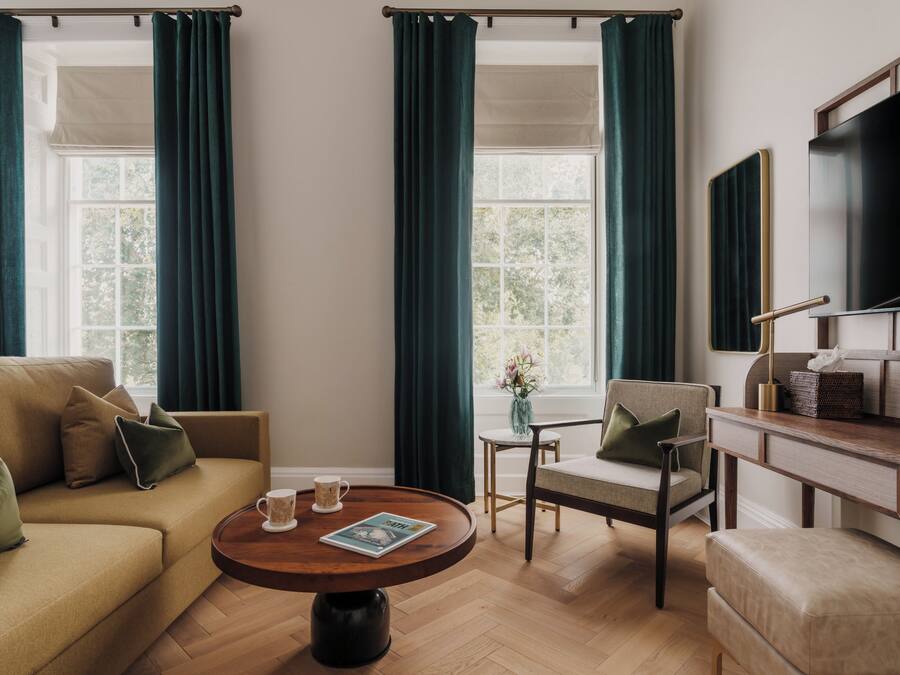 A well-lit living room with a sofa, armchairs, a coffee table, and a television.
