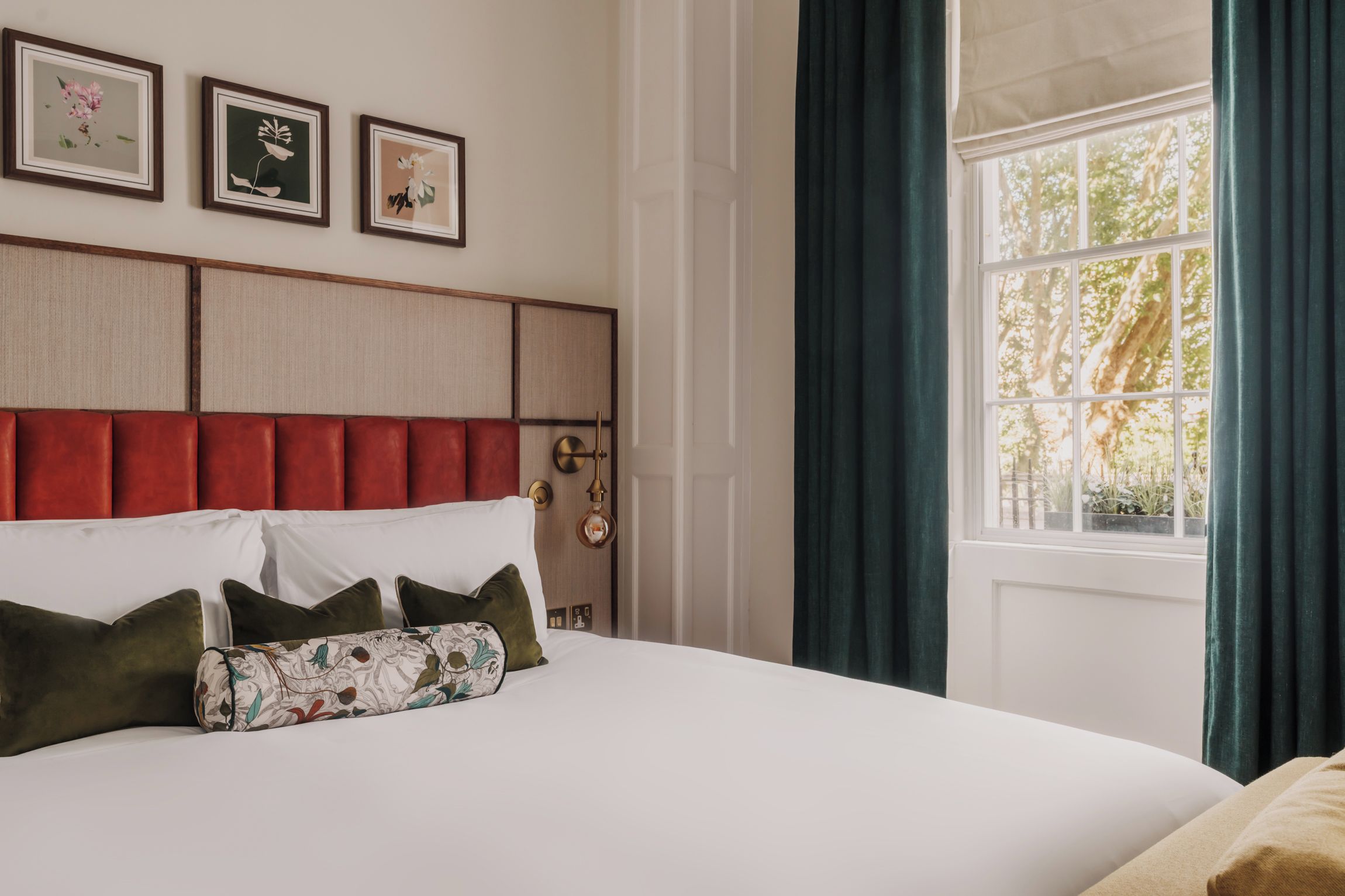 Una cama con cabecera, almohadas y una ventana con cortinas.