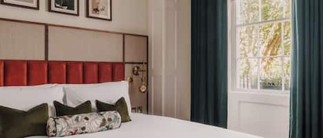 A bed with a headboard, pillows, and a window with curtains.