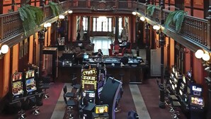 Un atrio espacioso con techo alto, balcones ornamentados y una zona de bar central con máquinas tragamonedas.