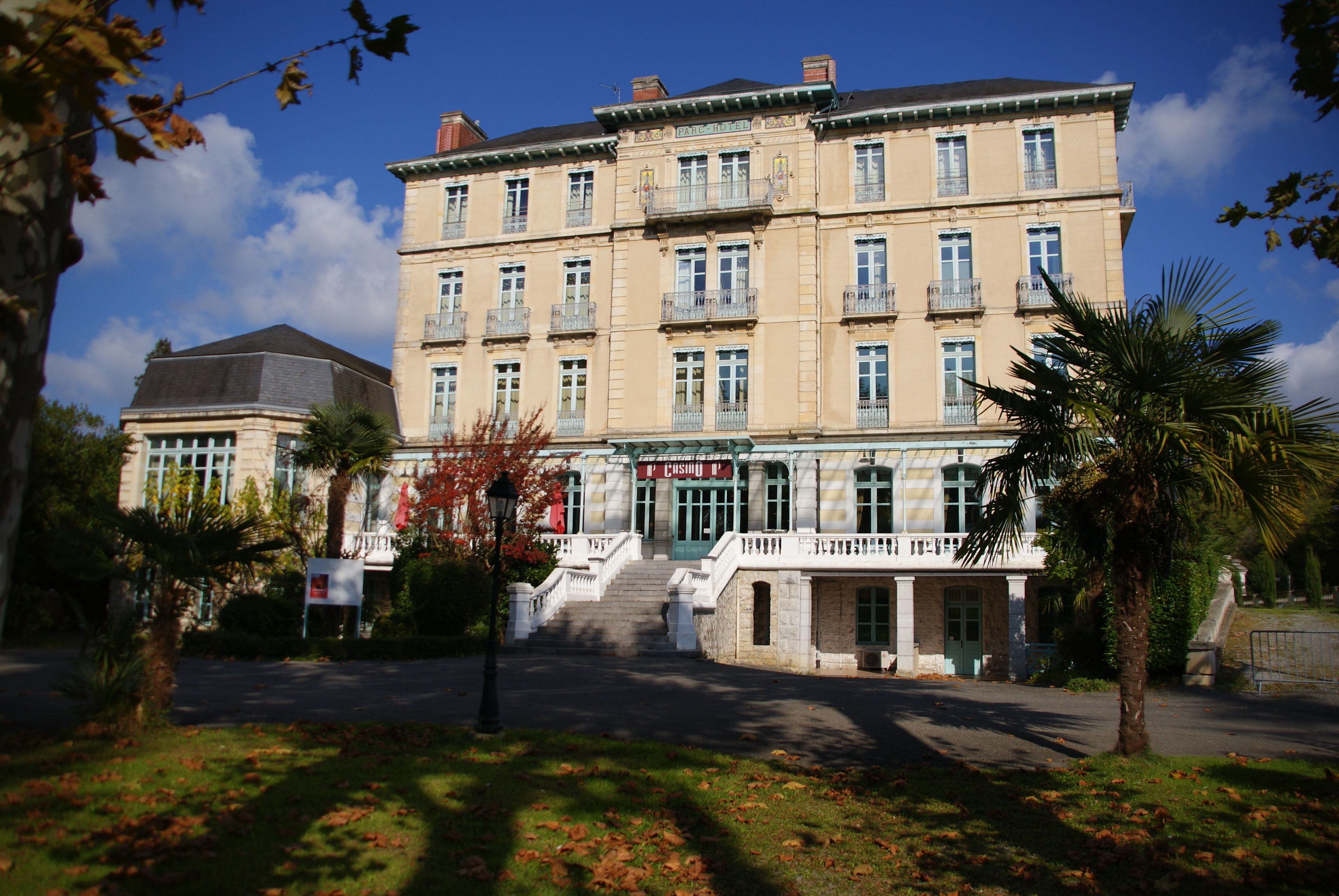 A multi-story building with a central entrance, large windows, and a balcony on the second floor.