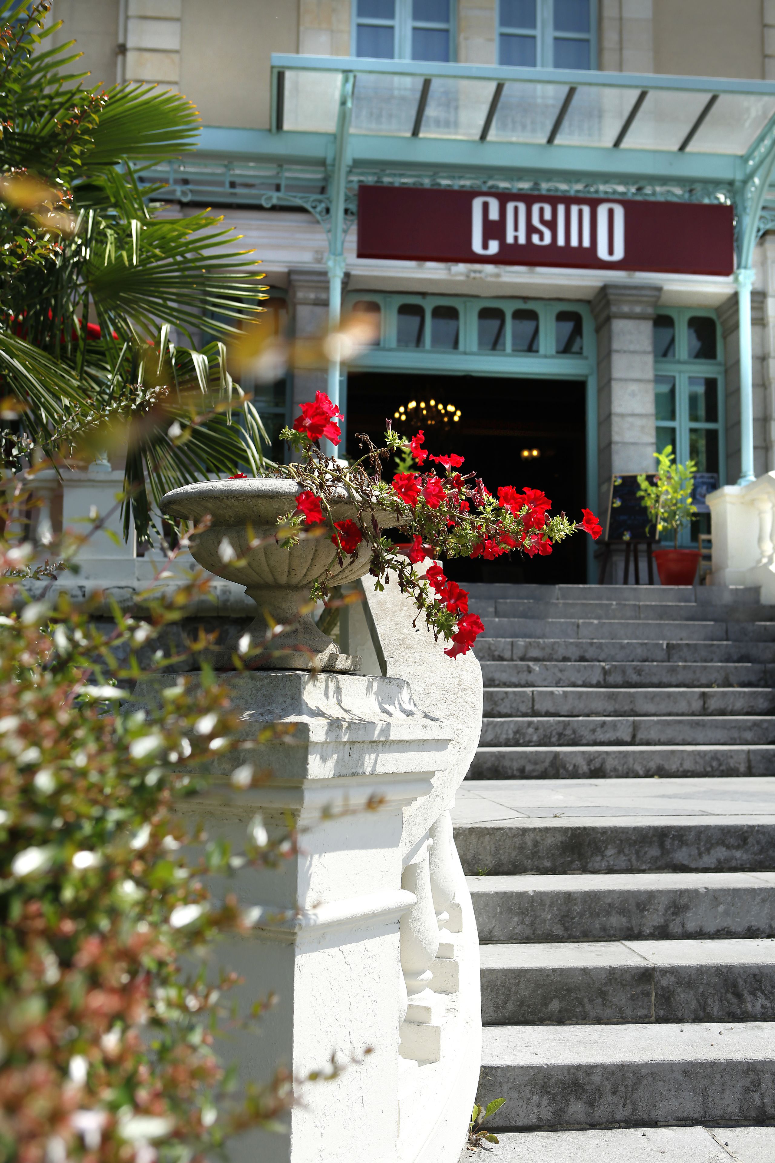 A building with a 'Casino' sign, stone steps, and a planter with red flowers.